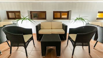Un coin salon avec un canapé et deux fauteuils, une petite table et des plantes en pot.