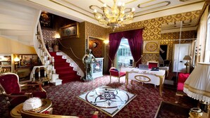 Ein luxuriöses Zimmer mit einer imposanten Treppe, einem Empfangsbereich und einem roten Teppichboden.