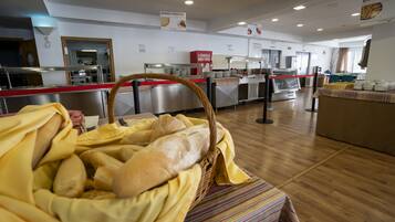Een buffetgedeelte met een broodmand, roestvrijstalen apparatuur en een strepen tafelkleed.