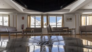 A spacious room with a large, shiny, reflective floor, several chairs, and a table. - Albergue Inturjoven Sierra Nevada - Hostel (Monachil)