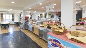 A cafeteria with a buffet setup, including a variety of food items and a sign for 'Menorquina'. - Albergue Inturjoven Sierra Nevada - Hostel (Monachil)