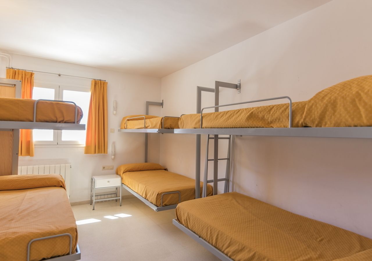 Une chambre de dortoir avec des lits superposés, un bureau et une fenêtre avec des rideaux.