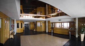 A spacious lobby with wooden paneling, a central open area, and a mezzanine level. - Albergue Inturjoven Sierra Nevada - Hostel (Monachil)