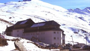 A large building with a sloped roof, situated on a snowy mountain slope. - Albergue Inturjoven Sierra Nevada - Hostel (Monachil)