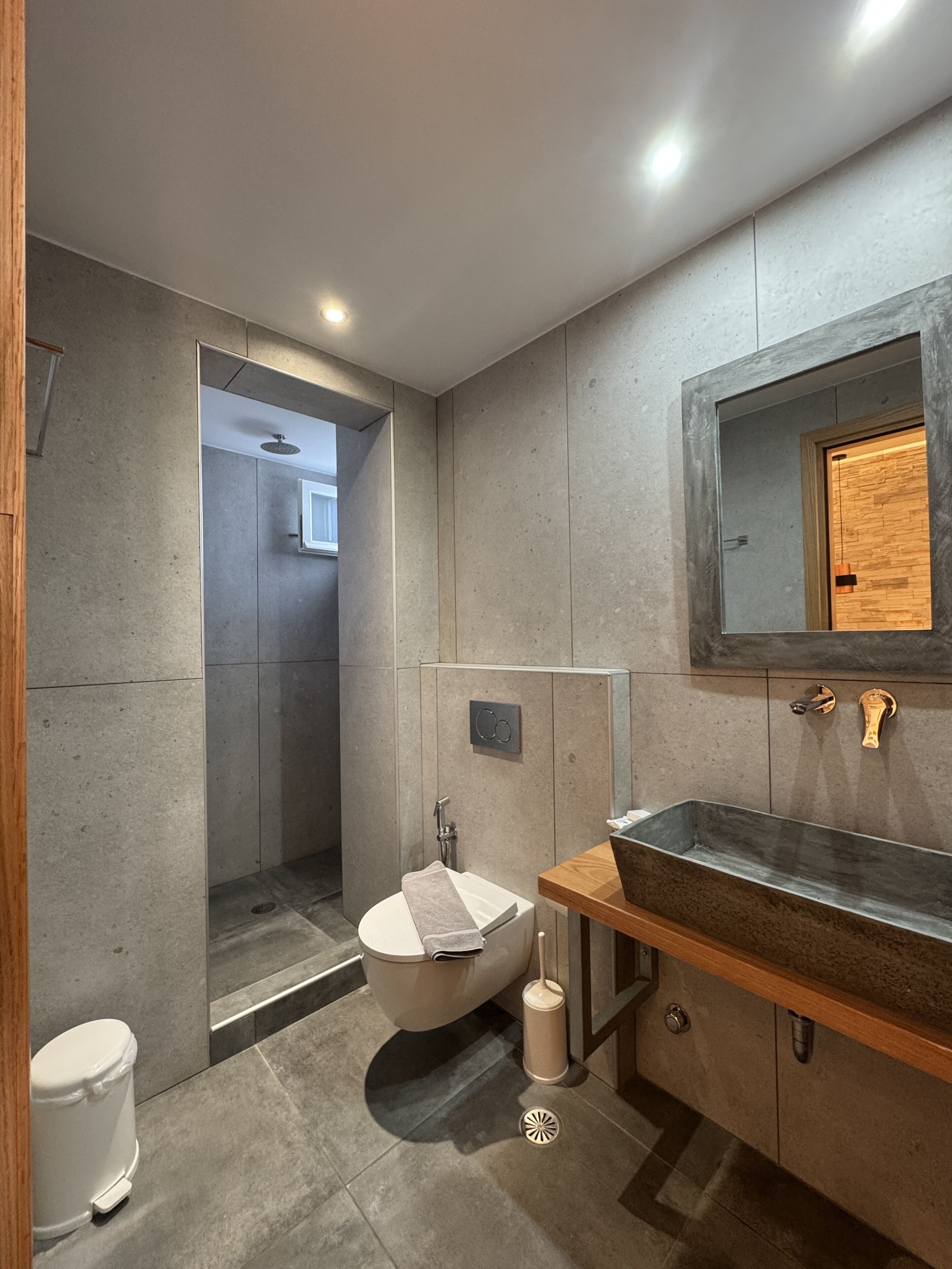 A modern bathroom with a freestanding bathtub, a sink with a wooden countertop, and a mirror with a wooden frame.