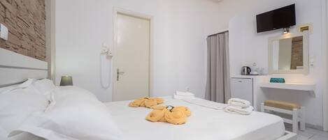 Habitación de hotel con cama, escritorio, espejo y televisor.