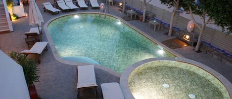 Een zwembadgedeelte met ligbedden en een jacuzzi.