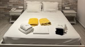 Une chambre moderne avec un mur décoré d’un motif en pierre, un lit avec une literie blanche, deux tables de chevet avec des lampes et un téléphone sur l’une des tables.