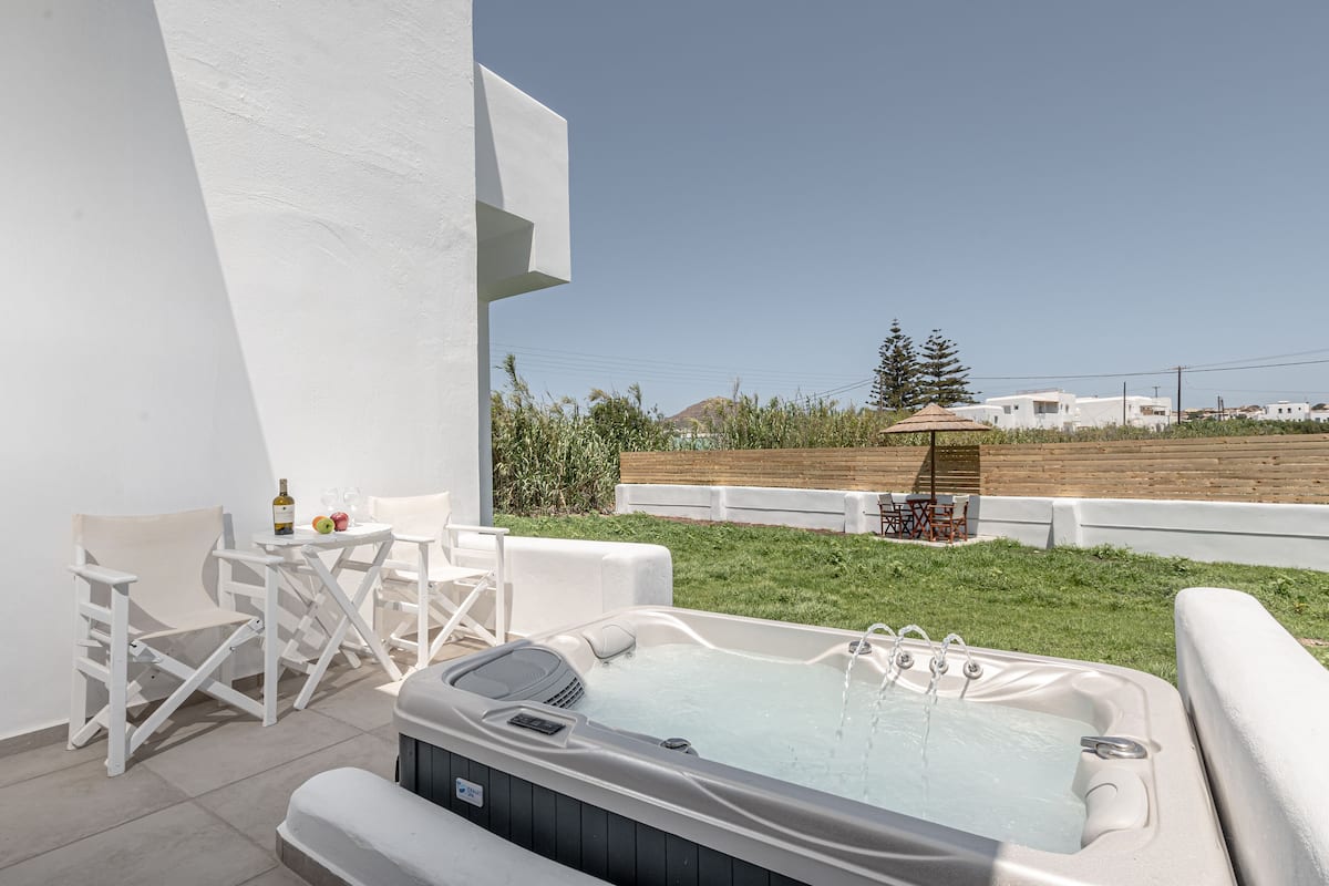 A hot tub with a view of a grassy area and buildings in the background.