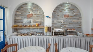 Un espace dédié au petit-déjeuner avec des murs en pierre, un buffet et des tables en marbre.