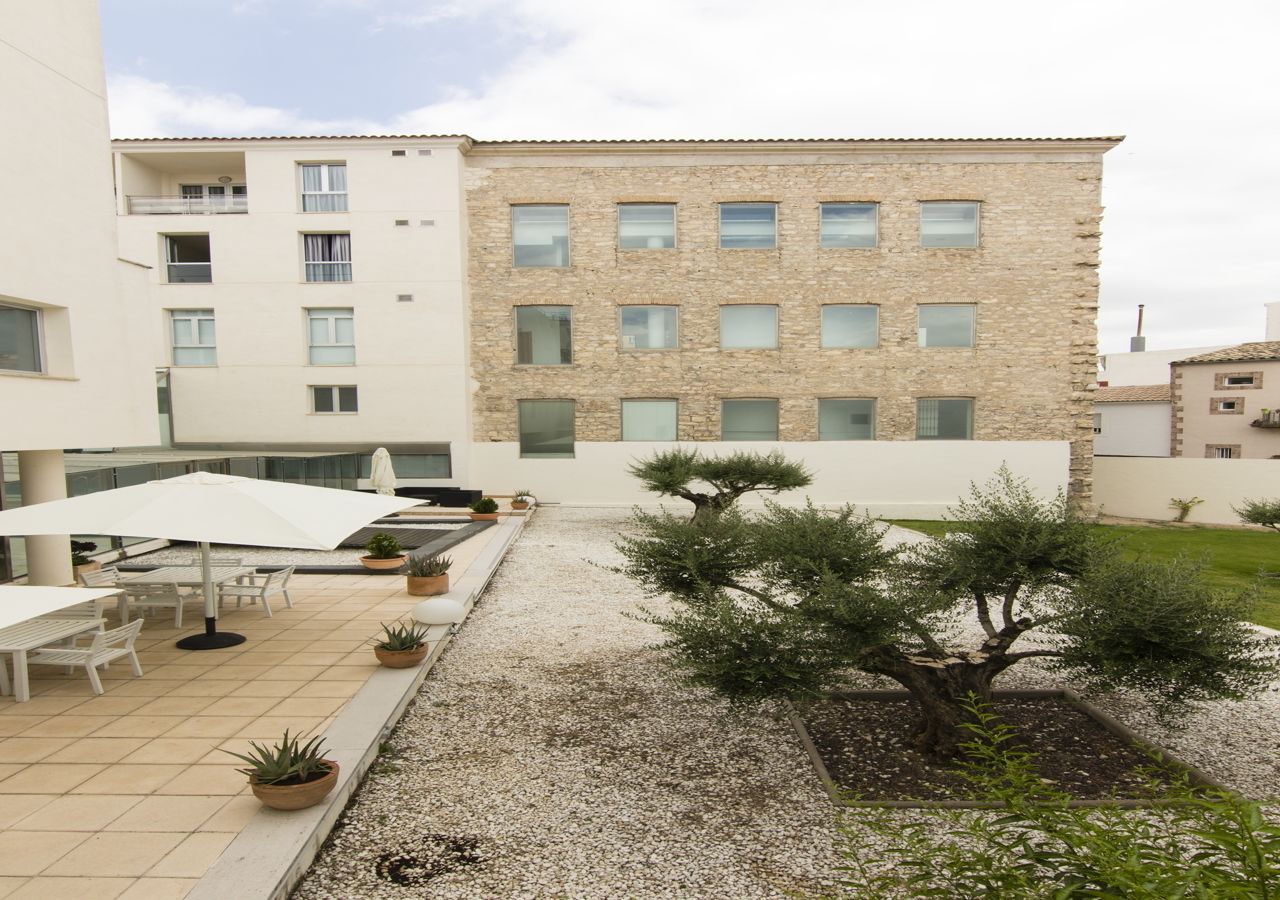 A courtyard with outdoor seating, a stone building, and a small tree.