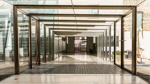 A corridor with glass walls and a wooden floor, leading to a building entrance. - Albergue Inturjoven & Jaen - Hostel (Jaén)