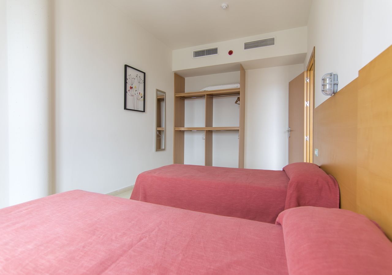 A bedroom with two beds, a wooden wardrobe, and a framed picture on the wall.