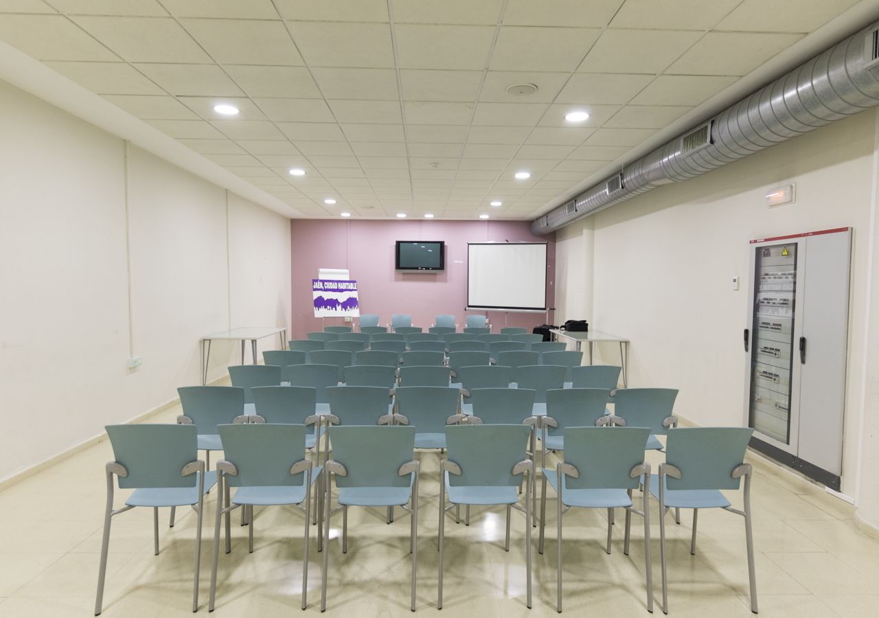 A conference room with rows of chairs, a projector screen, and a whiteboard.
