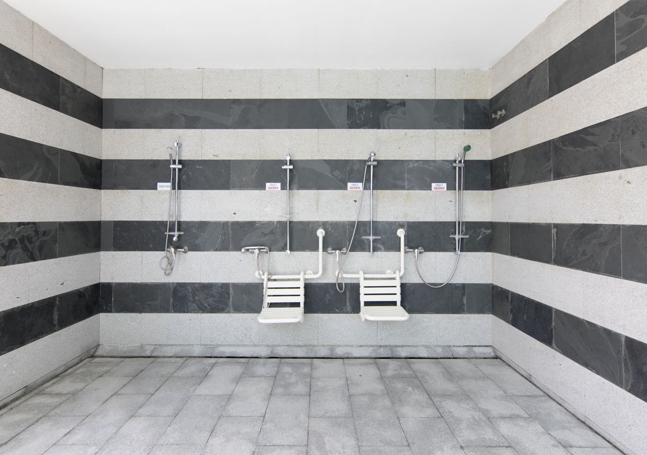 Un baño con paredes a rayas blancas y negras, dos toalleros blancos y piso de baldosas.