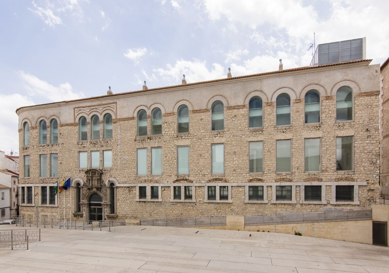 Un edificio de piedra con una entrada central, varias ventanas y una bandera.