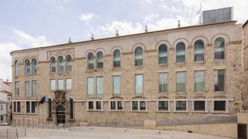 Un edificio de piedra con una entrada central, varias ventanas y una bandera.