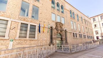 Un edificio histórico de piedra con entrada central, múltiples ventanas y exhibición de banderas.
