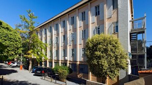 Un edificio de varios pisos con fachada plana, múltiples ventanas y una entrada con portón.