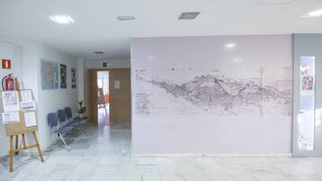 Un vestíbulo con un gran mural en la pared, un mostrador de recepción y una zona de estar con sillones.