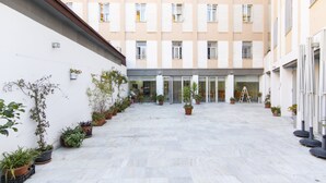 Un patio con plantas en macetas, la entrada de un edificio y una escalera.