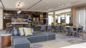 A modern hotel lobby with a bar, seating area, and a kitchen in the background. - Courtyard Milwaukee Airport (Milwaukee)