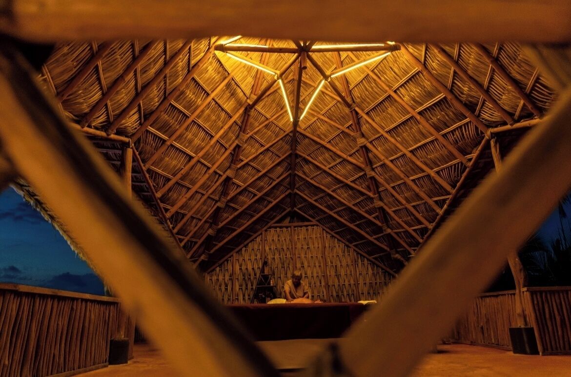 Una estructura de techo de paja con una zona de estar central y vistas al exterior.
