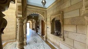 Un pasillo con arcos y columnas decorativas, un candelabro colgante y un suelo de mármol.