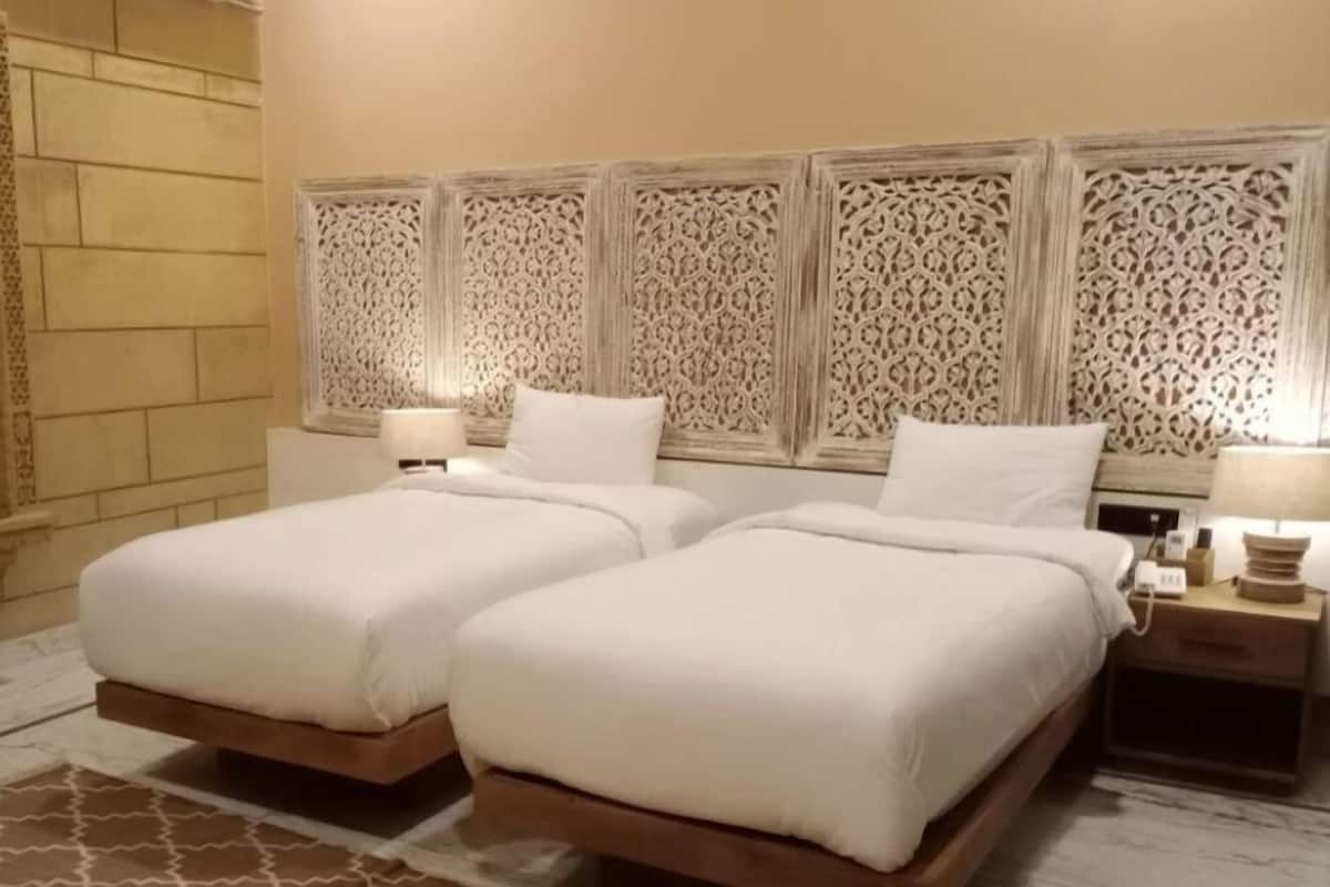 Een hotelkamer met twee bedden, een gestreept hoofdeinde en een tapijtrand.