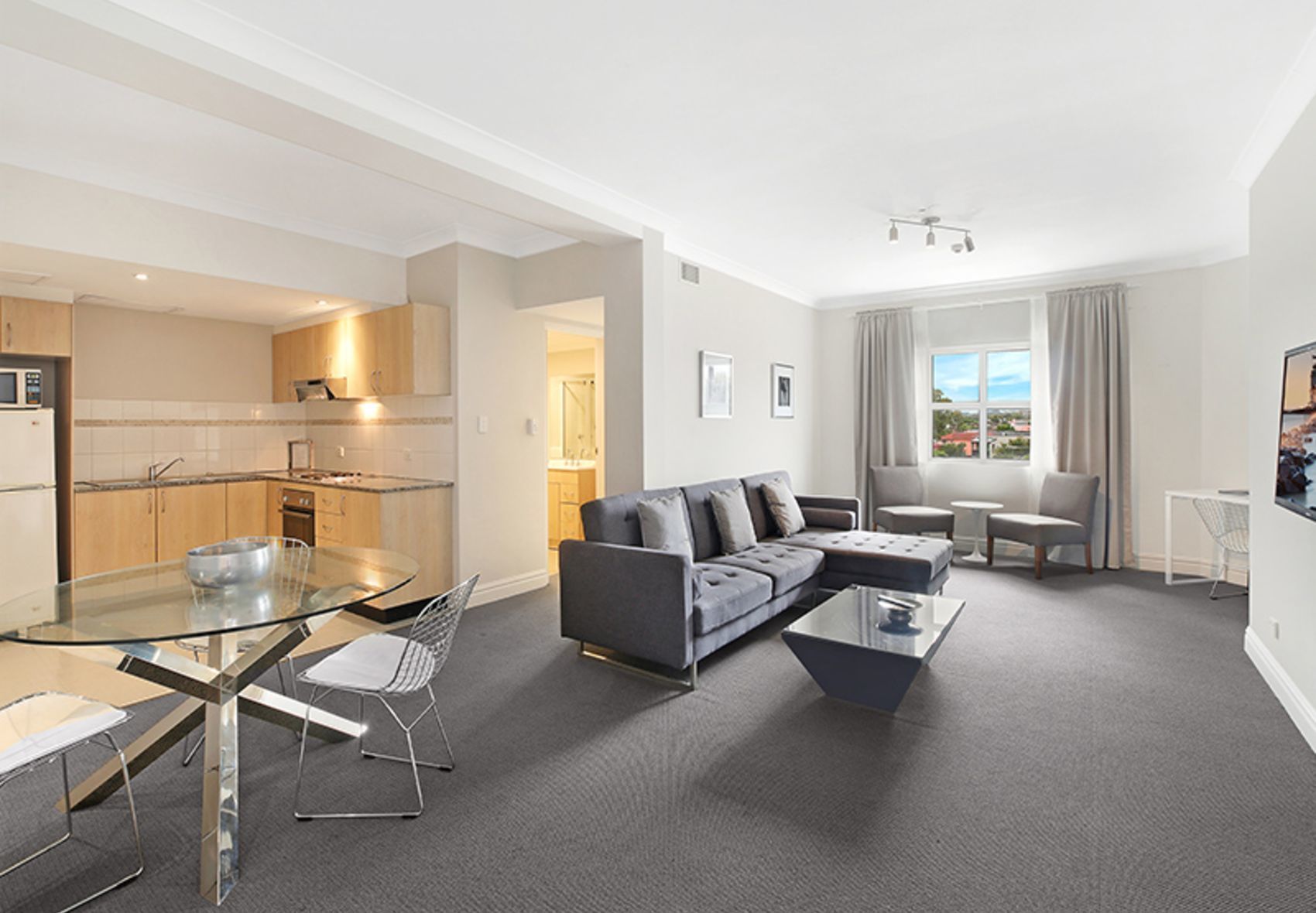 A modern apartment with a living room, dining area, and kitchen.