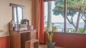 A room with a wooden desk, a mirror, a potted plant, and a view of the ocean. - Soka Indah Restaurant & Bungalows (Selemadeg)