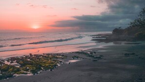 A beach with waves, rocky areas, and a sunset. - Soka Indah Restaurant & Bungalows (Selemadeg)