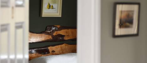 A bedroom with a wooden headboard, a framed painting of pears, and a bed with white bedding.