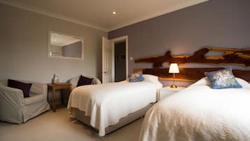 A hotel room with two beds, a sofa, a small table, and a lamp.