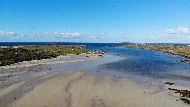 A coastal landscape with a sandy beach, a calm sea, and a distant island. - Sharamore House (Clifden)