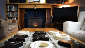 A living room with a fireplace, a television, and a table with various items. - Sharamore House (Clifden)