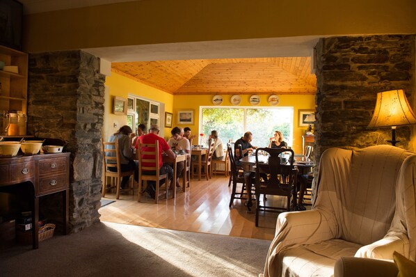 A dining area with stone walls, wooden ceiling, and a view of the outdoors. - Sharamore House (Clifden)