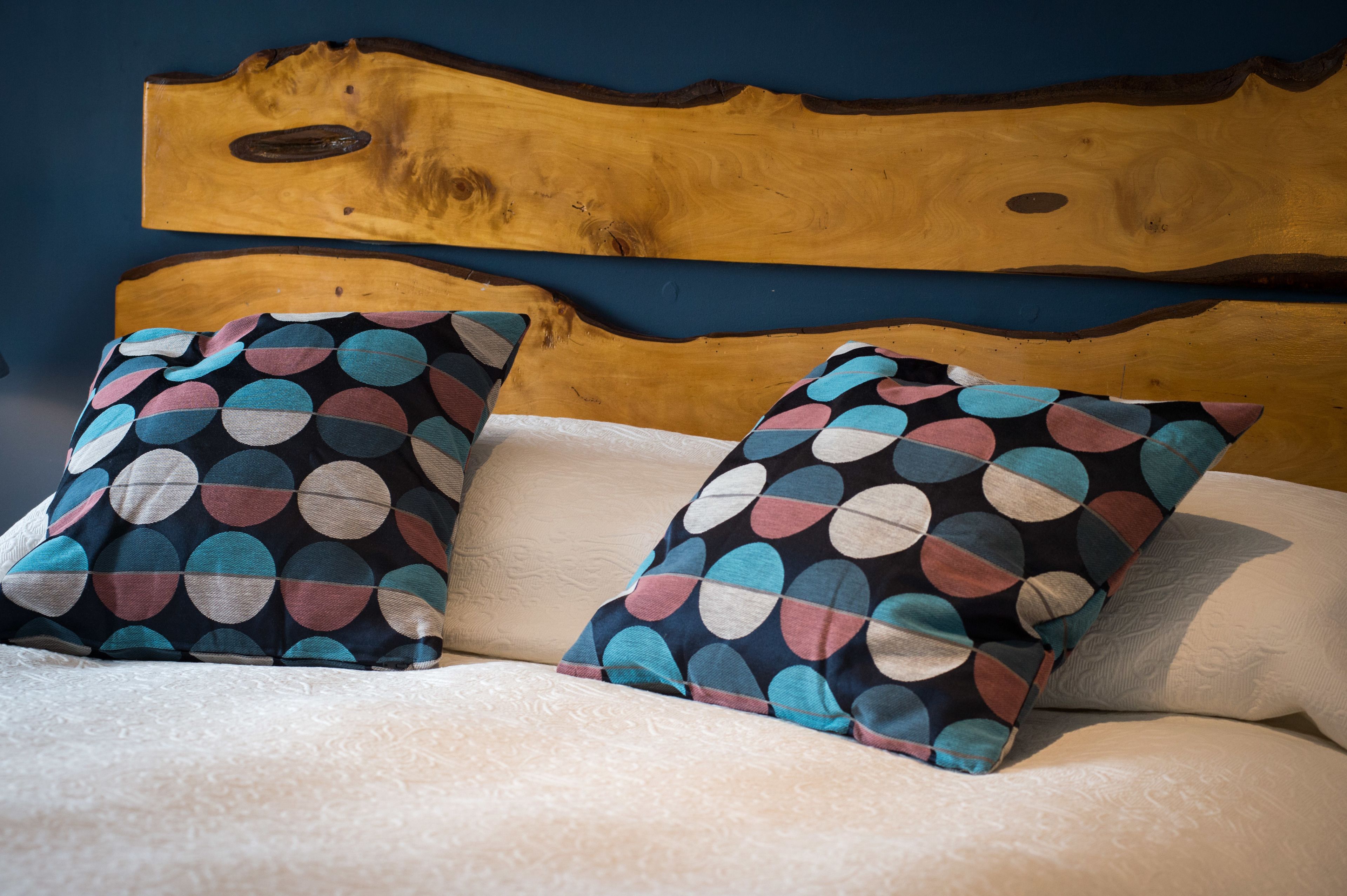 A bed with two pillows featuring a polka dot pattern, a wooden headboard, and a textured white bedspread.