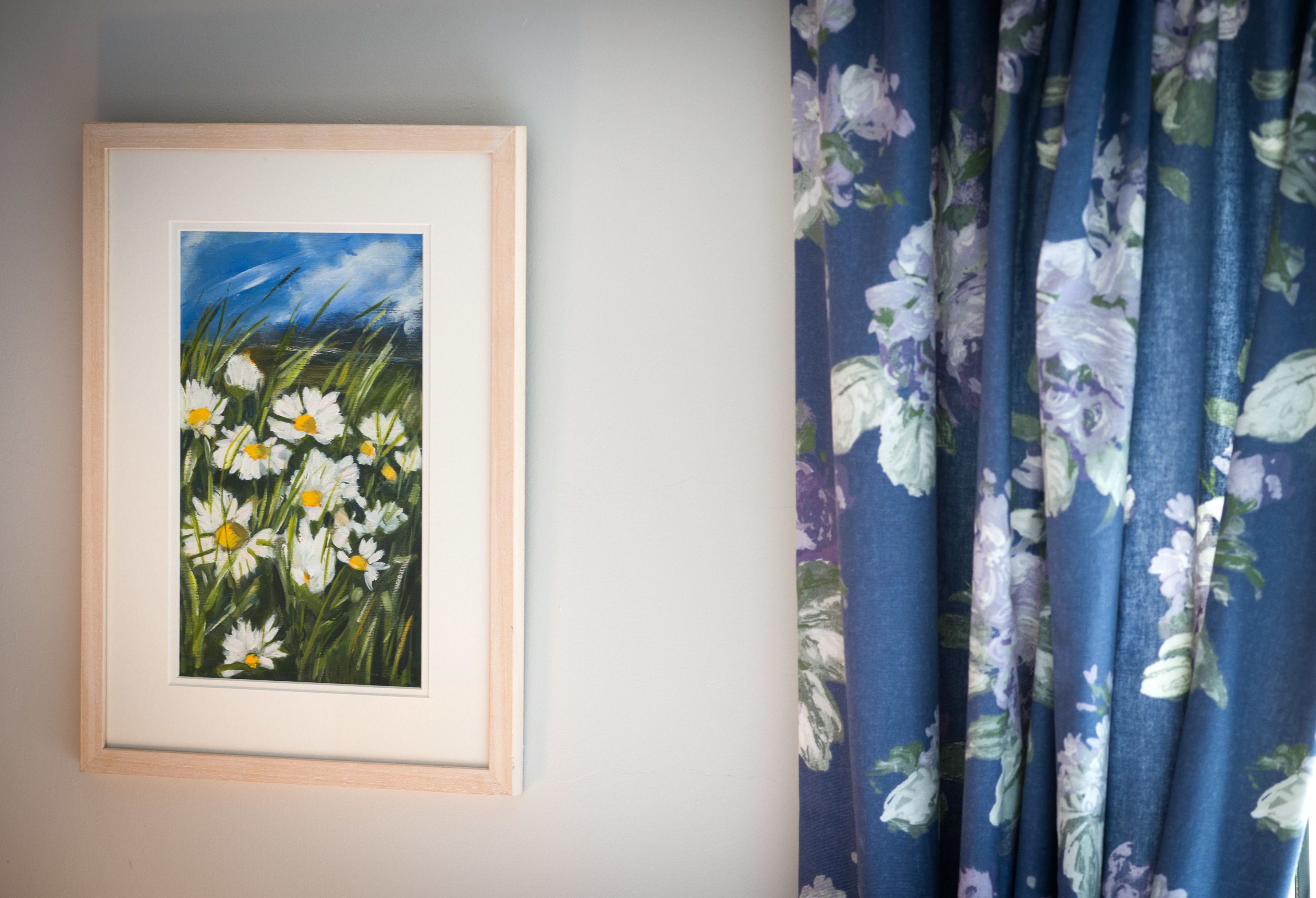 A framed painting of daisies on a wall.