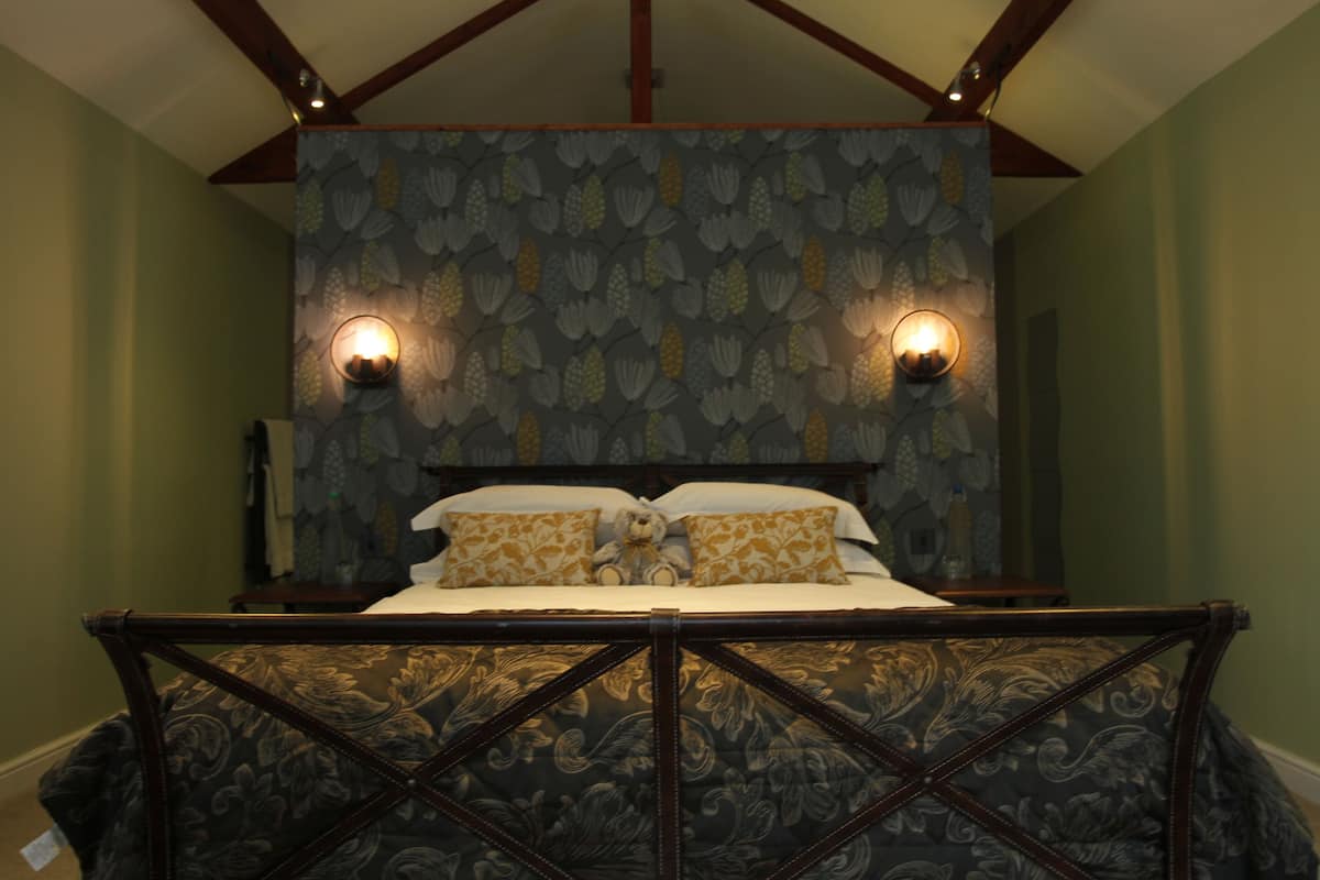 Cama com cabeceira estampada escura e papel de parede floral.