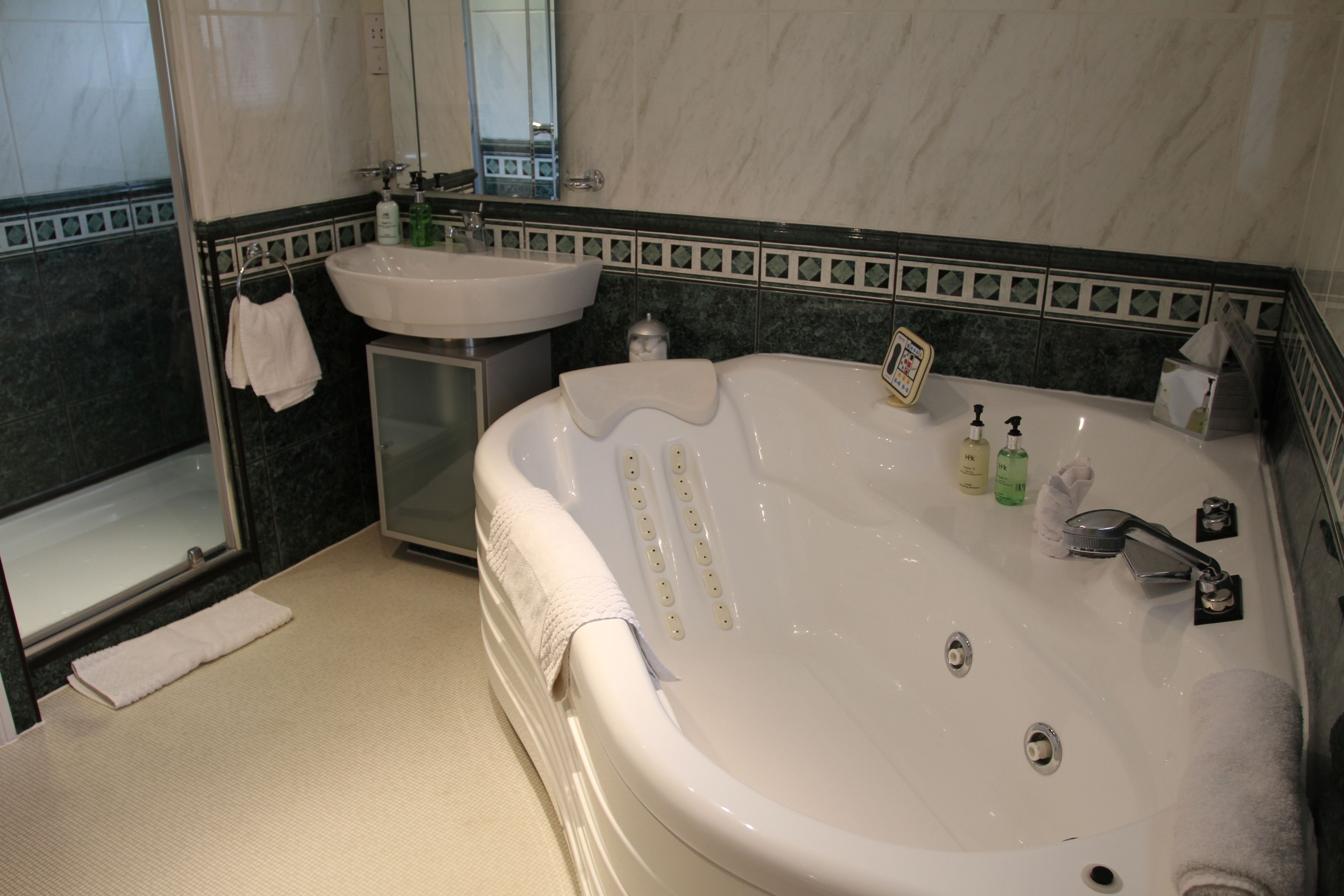 A bathroom with a large bathtub, a sink, and a mirror.