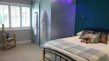 Un dormitorio con cama, una silla, un ventanal y una pared con lámpara.