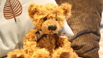 Un oso de peluche suave con un lazo escocés sobre una cama con almohadas.