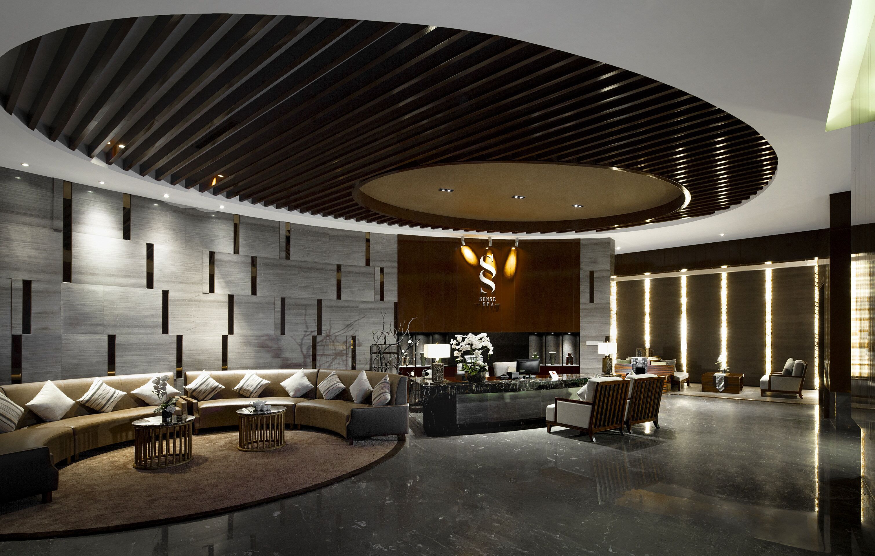 Eine moderne Lobby mit einer gebogenen Rezeption, Sofas und einem großen, runden Deckenstil.