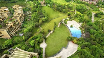 An aerial view of a residential area with a swimming pool, green lawns, and a church.