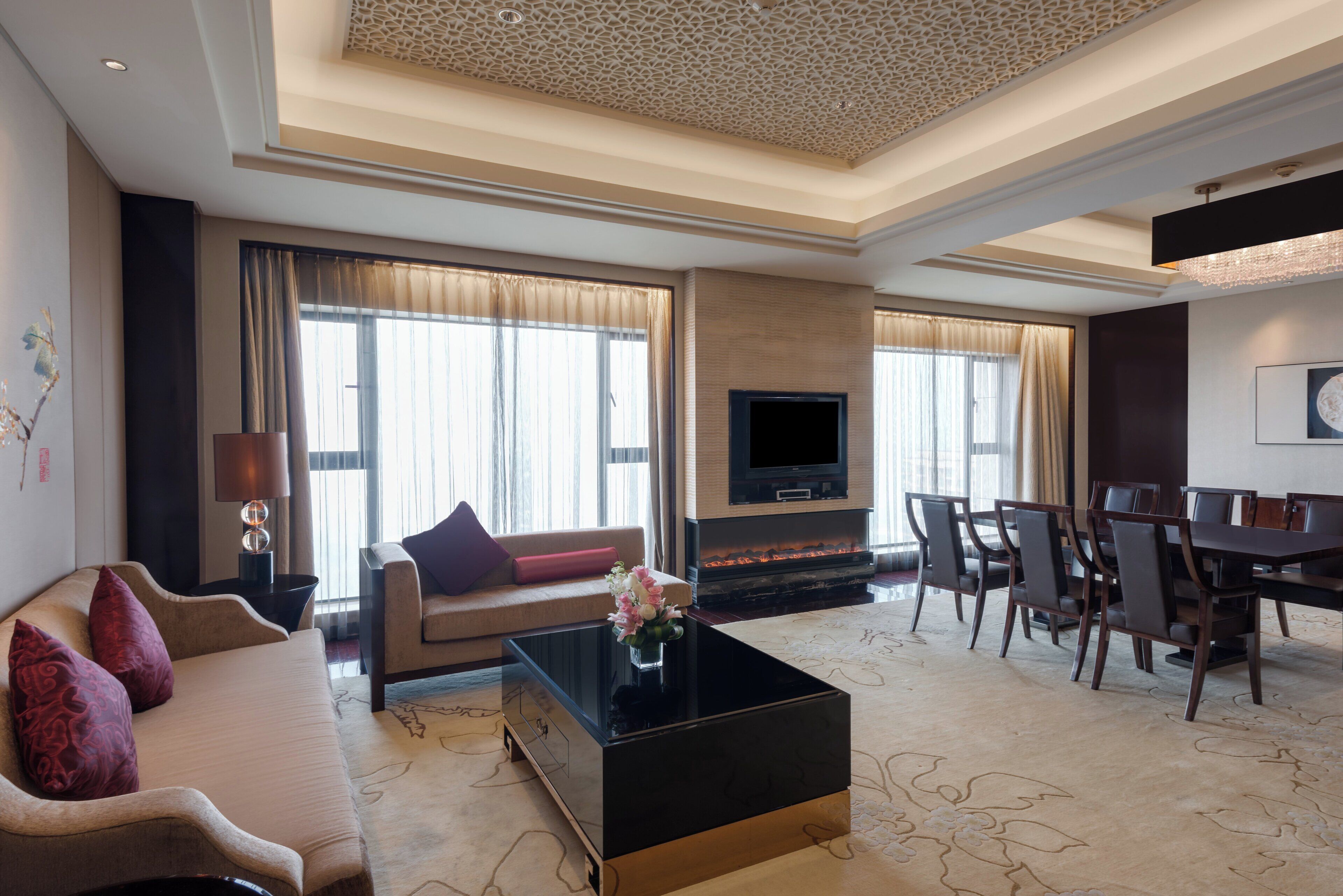 A modern living room with a sofa, coffee table, fireplace, TV, and dining area.