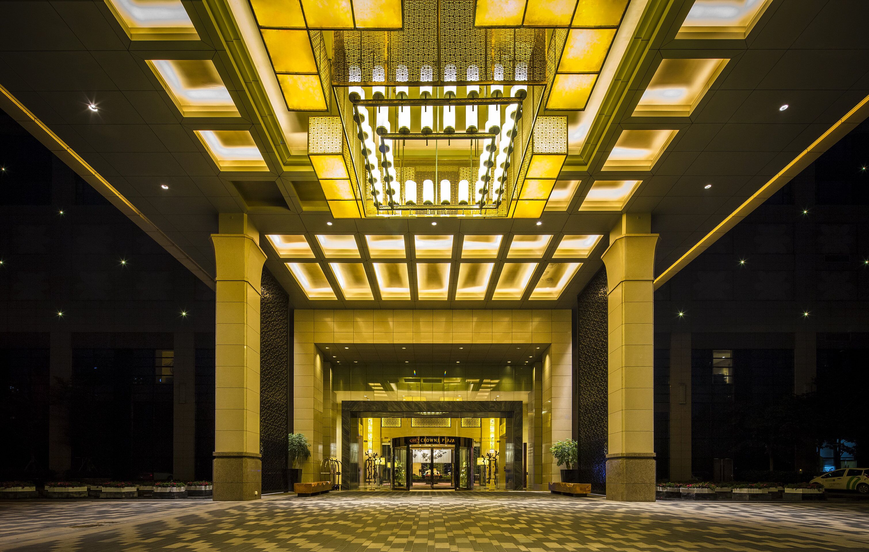 A hotel entrance with a geometric ceiling design and a checkered floor pattern.