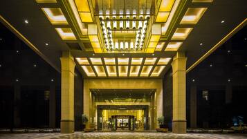 A hotel entrance with a geometric ceiling design and a checkered floor pattern.