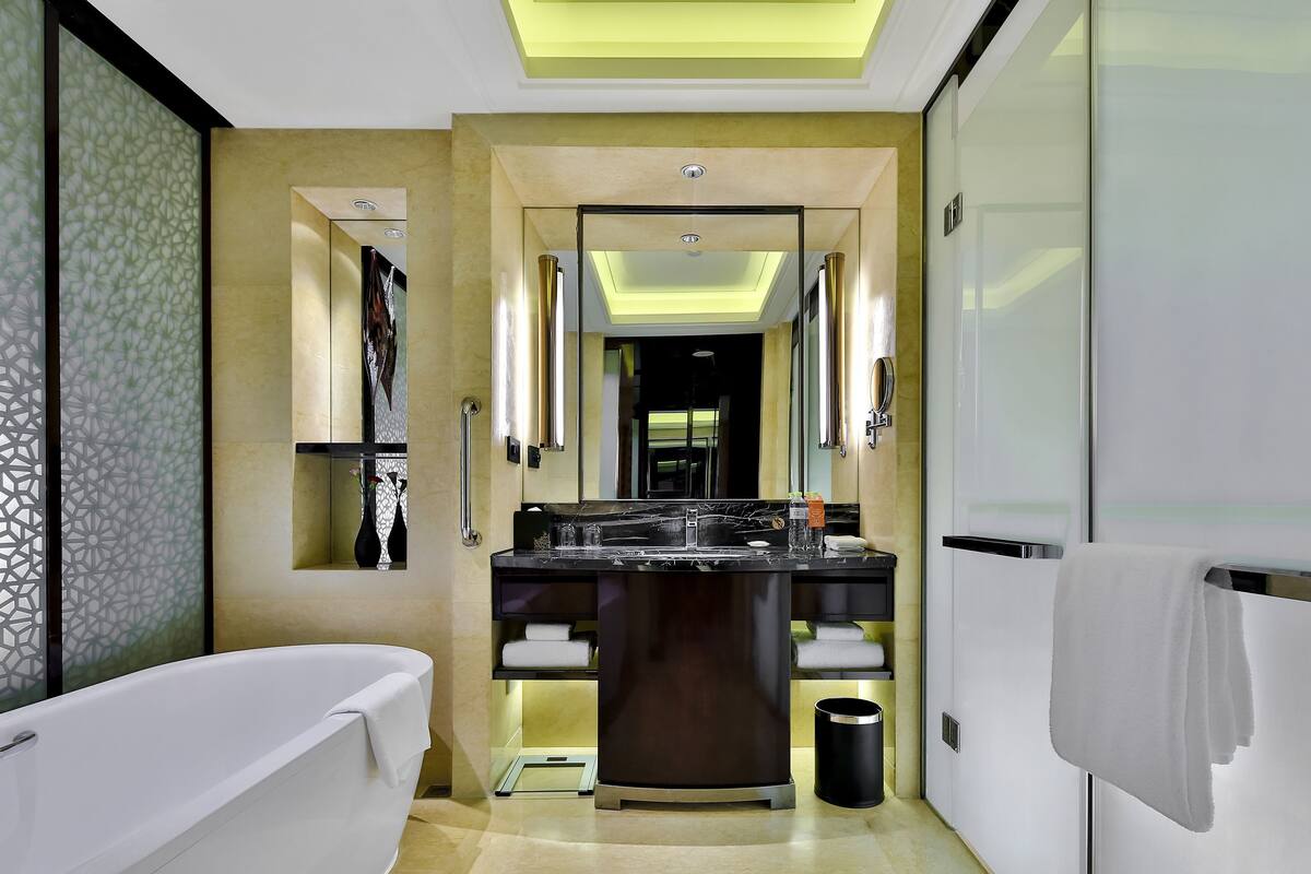 A modern bathroom with a freestanding bathtub, a vanity with a mirror, and a towel rack.