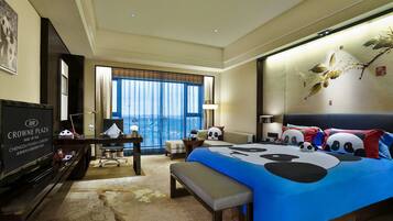A hotel room with a large bed, a desk, a television, and a view of the outdoors.